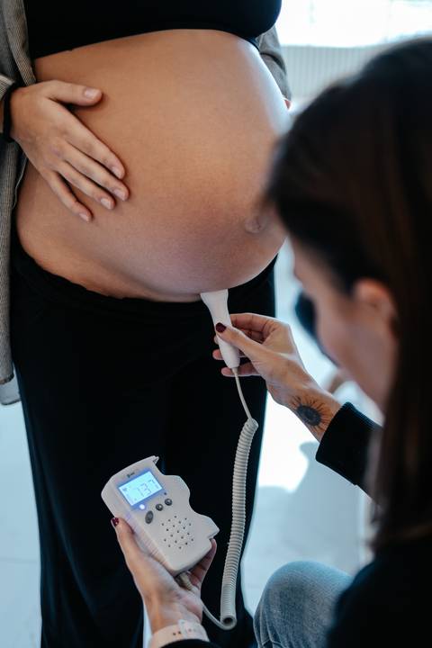 Doula utilizando o sonar para verificar e monitorar os batimentos cardíacos do bebê.'