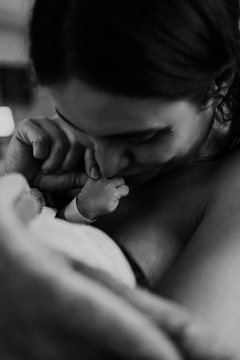 Versão em preto e branco do close da mãe beijando a mão do recém-nascido.'