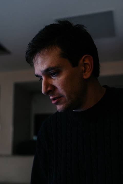 Retrato do pai observando o recém-nascido com olhar emocionado.'