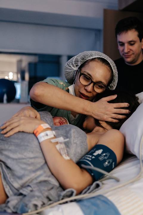 Profissional de saúde abraçando com carinho a mãe na cama do hospital.'