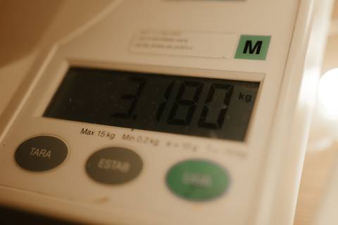Balança digital hospitalar marcando o peso do recém-nascido (3,180 kg).'