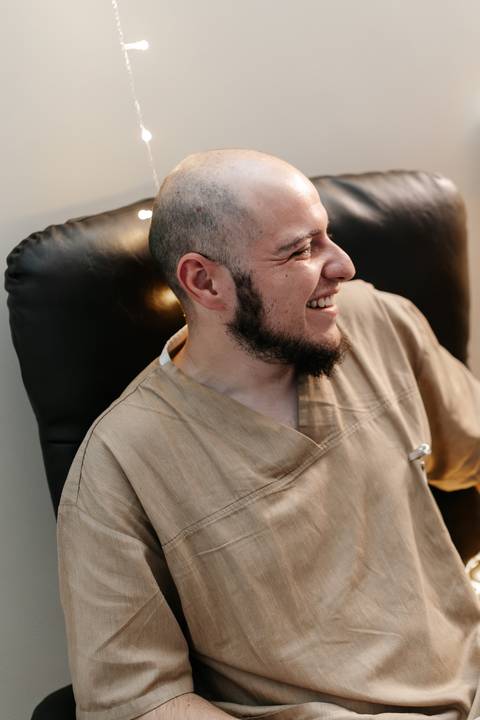 Acompanhante sorrindo aliviado e descontraído no quarto de hospital.'
