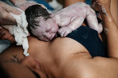 Recém-nascido no peito da mãe logo no primeiro minuto de vida após o nascimento.'