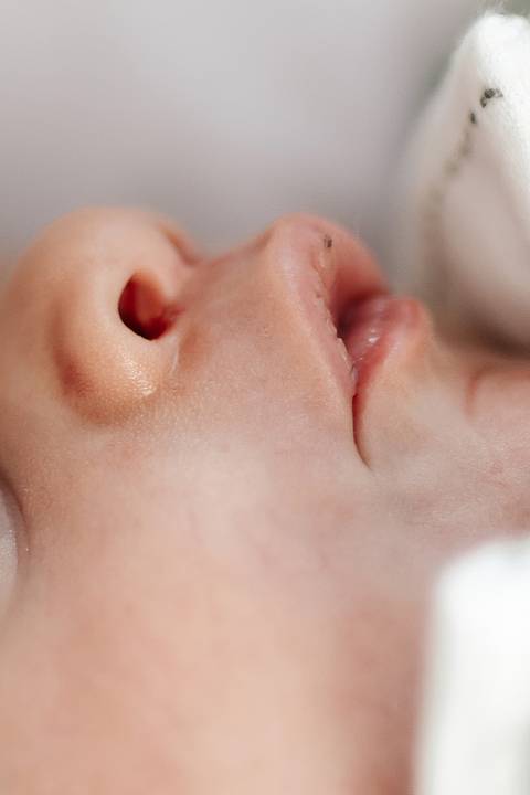 Close-up de perfil destacando o nariz, os lábios e o queixo do bebê.'
