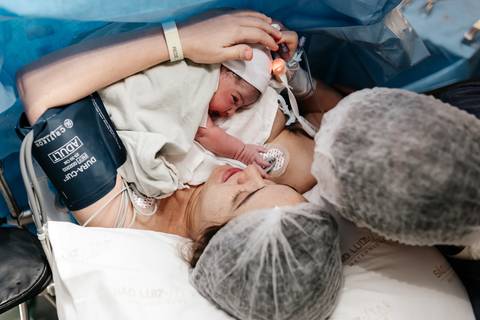 Visão superior do bebê aconchegado no peito da mãe logo após o parto.'