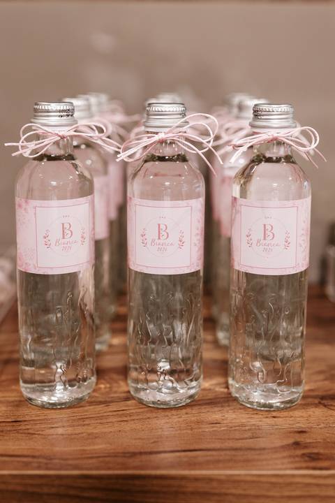 Garrafinhas de água personalizadas com rótulo rosa para lembrancinha de maternidade da Bianca.'