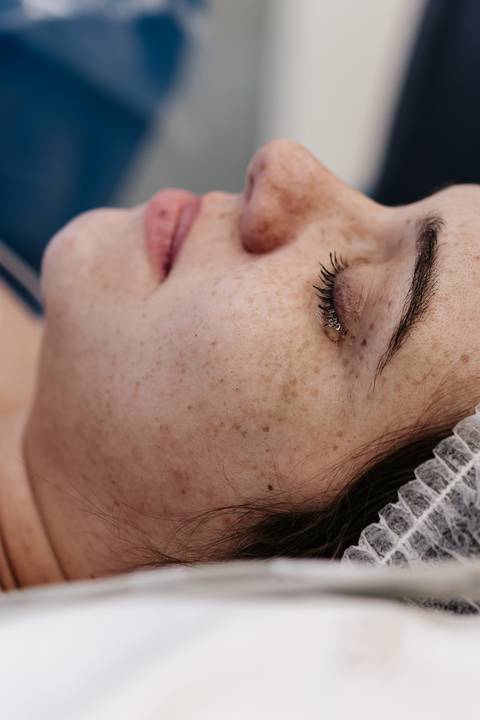 Close-up emocionado no rosto da mãe com lágrimas nos olhos logo após o nascimento.'