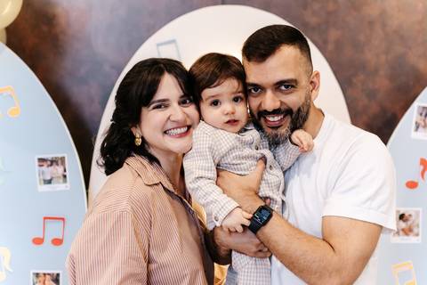 Close-up da família sorrindo abraçada durante a celebração do aniversário.'