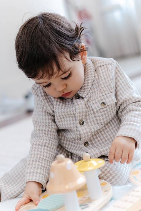 Bebê concentrado brincando no chão durante a festa de aniversário.'