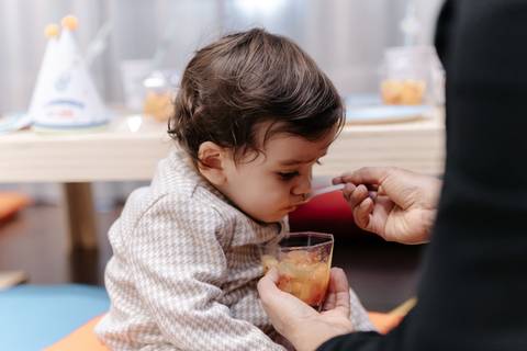 Aniversariante recebendo comida na boca durante a festa.'