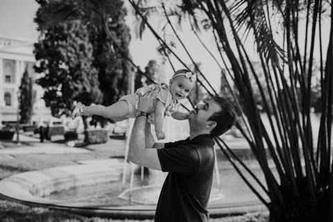 Versão em preto e branco do pai brincando de levantar a filha no ar.'
