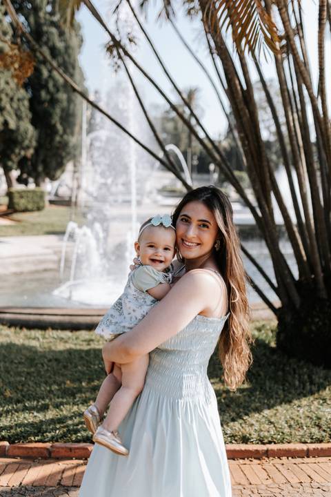 Retrato de mãe e filha sorrindo juntas em dia ensolarado no parque.'