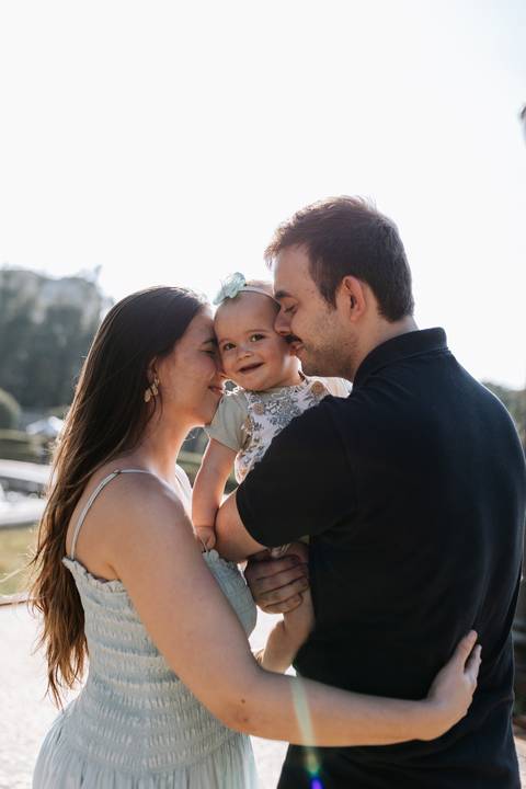 Retrato de família em close-up com o casal e a filha de rostos colados.'