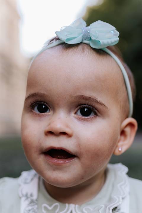 Close-up nos olhos expressivos da bebê em momento espontâneo.'