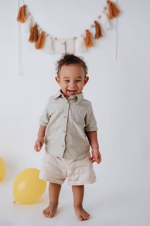 Bebê sorrindo radiante enquanto anda em direção à câmera.'