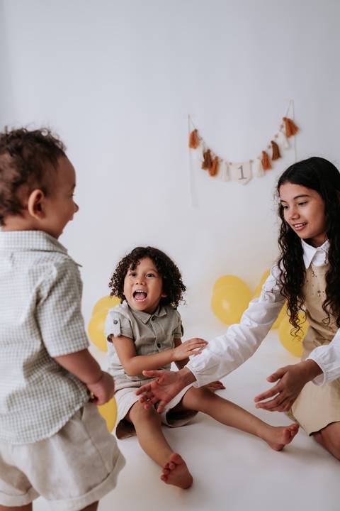 Três irmãos brincando e se divertindo juntos no chão do estúdio.'