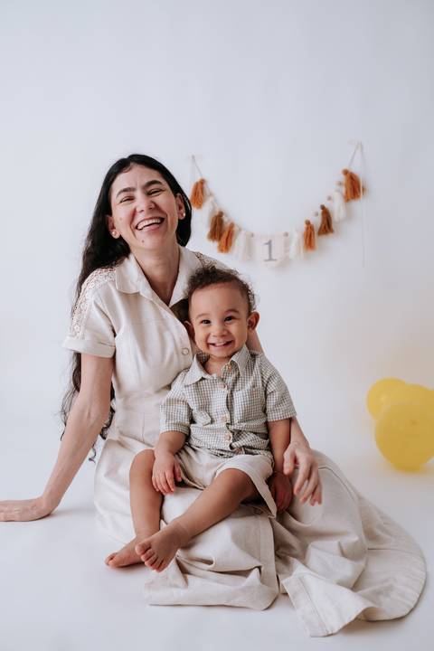 Mãe sorridente abraçando o bebê sentado em seu colo.'