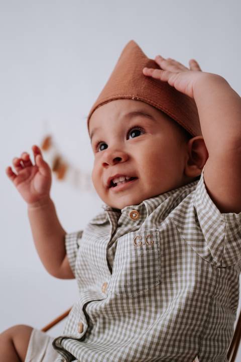 Bebê em plano contraponto com os braços levantados e olhar surpreso para o alto.'