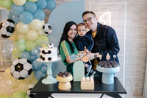 aniversariante com os pais, diante da decoração da festa de 1 ano'