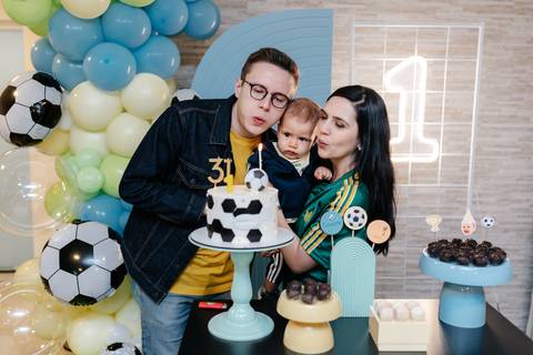 Familia comemorando seu primeiro aniversário junto à mesa do bolo'
