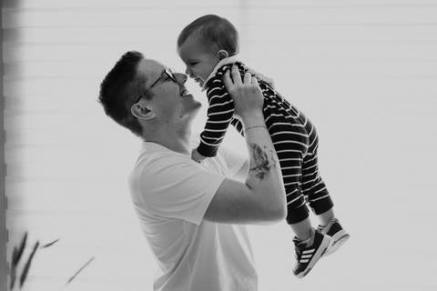 Pai brincando com filho durante o ensaio em família antes da festa de 1 ano.'