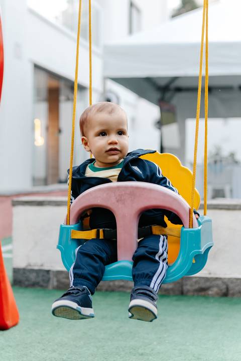 Bebê se divertindo no balanço durante a festa de 1 ano.'