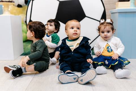 Bebê comemorando seu primeiro aniversário ao lado de outras crianças durante a festa'