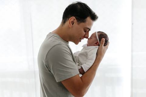 Pai e bebê em um momento íntimo e afetivo durante os primeiros dias.'