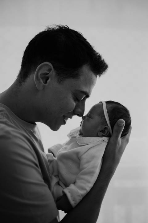 Pai e bebê em um momento íntimo e afetivo durante os primeiros dias.'