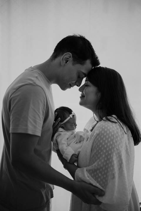 Familia aconchegado em seu quartinho durante o ensaio de primeiros dias em casa.'