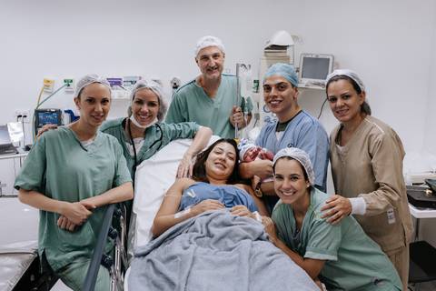 Pais e equipe medica reunidos com o bebê durante os primeiros momentos em família.'