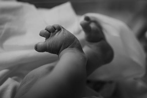 Detalhes das pequenas mãos e pés do bebê nos primeiros momentos de vida.'