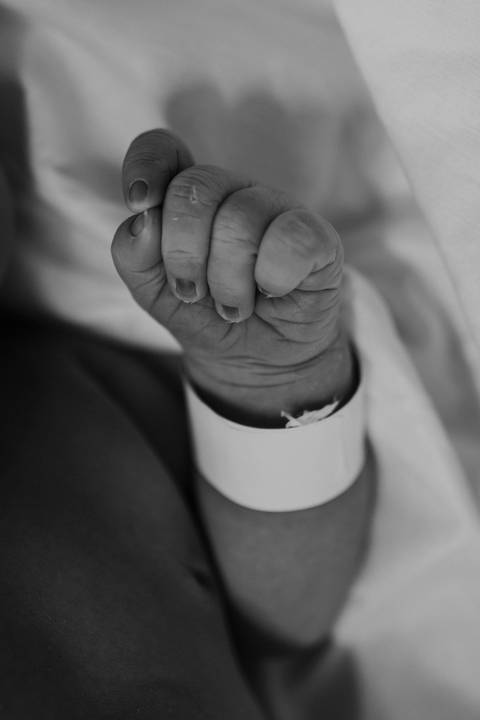 Detalhes das pequenas mãos e pés do bebê nos primeiros momentos de vida.'