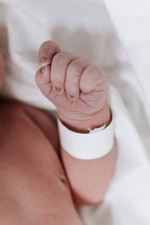 Detalhes das pequenas mãos e pés do bebê nos primeiros momentos de vida.'