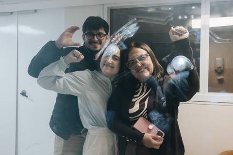 Familiares comemorando e acenando através do vidro da maternidade.'