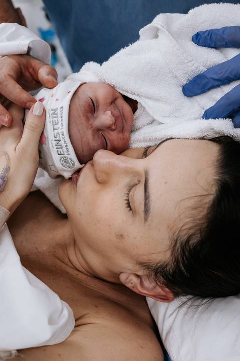 Mãe encostando o rosto e beijando a bochecha do bebê.'