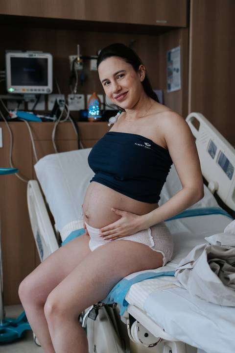 Gestante sentada acariciando a barriga.'
