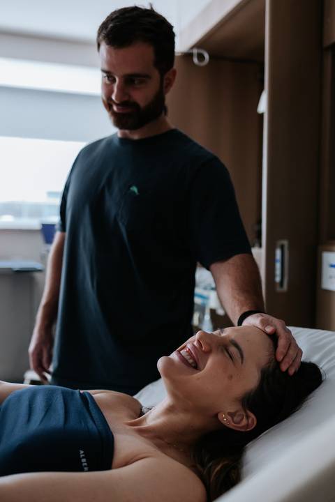 Acompanhante fazendo massagem na cabeça da gestante.'