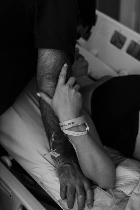 Mãos dadas do casal com pulseiras em preto e branco.'