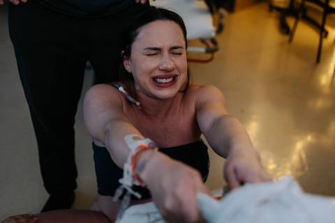 Gestante em esforço de parto segurando o tecido com apoio do acompanhante.'