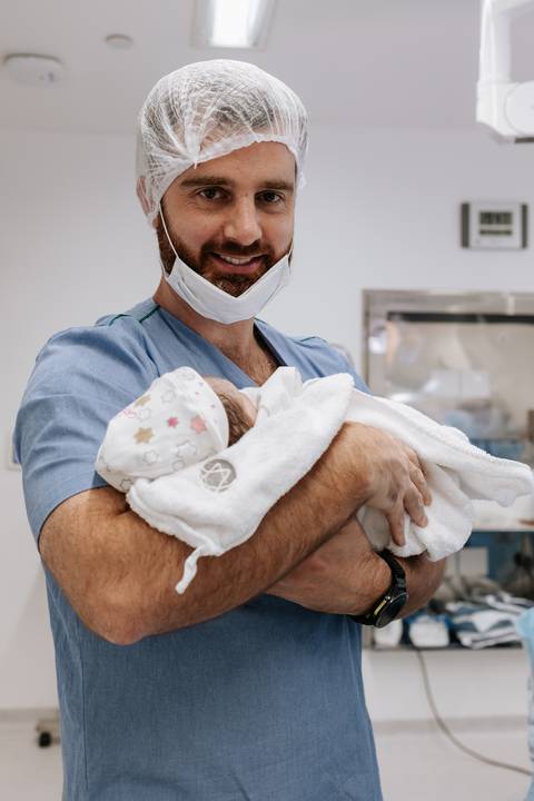 Pai sorridente segurando a filha aconchegada em seus braços.'