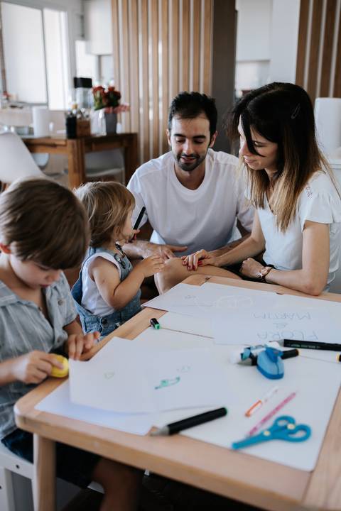 Família reunida ao redor da mesa de desenhos.'
