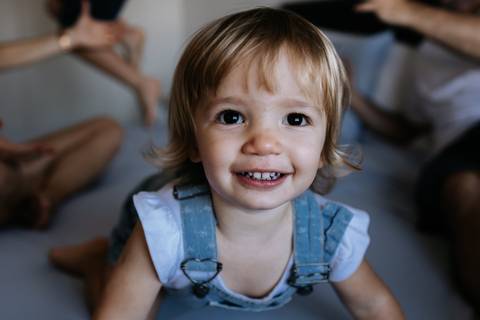 Close da menina sorrindo de joelhos na cama.'