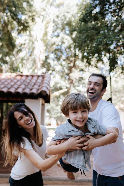 Família sorrindo junta ao ar livre no parque.'