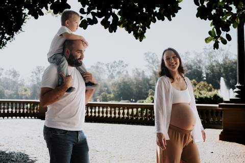 Família passeando sob a sombra das árvores do parque.'