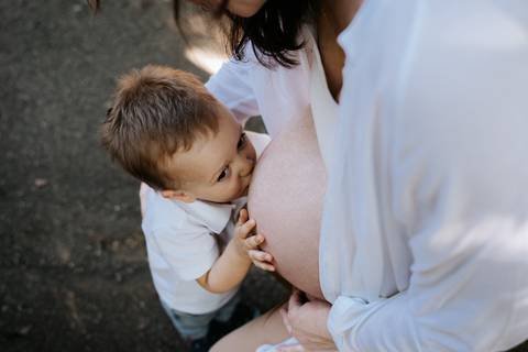 Menino dando um beijo afetuoso na barriga da mãe.'