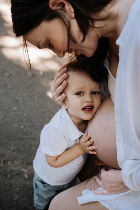 Menino abraçando a barriga da mãe gestante com carinho.'