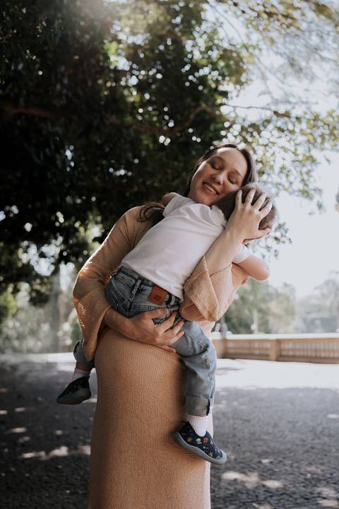 Mãe segurando o filho aconchegado em seus braços.'