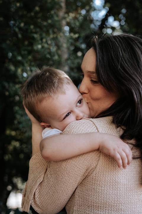 Mãe dando um beijo carinhoso na bochecha do filho.'