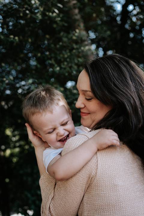 Close de mãe e filho sorrindo juntos no abraço.'